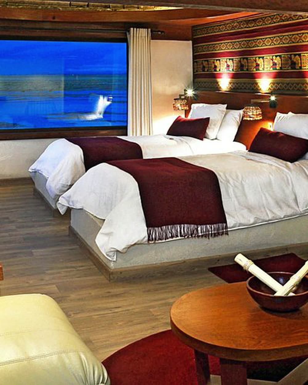Two timber beds against a wood-lined wall, a window open to the flats beyond &mdash; Palacio de Sal, Uyuni, Bolivia