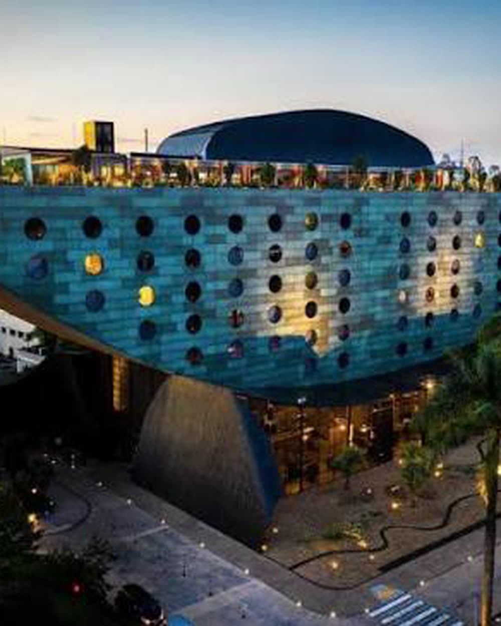 The curved hull with circular windows, city skyline at dusk &mdash; Hotel Unique, São Paulo, Brazil
