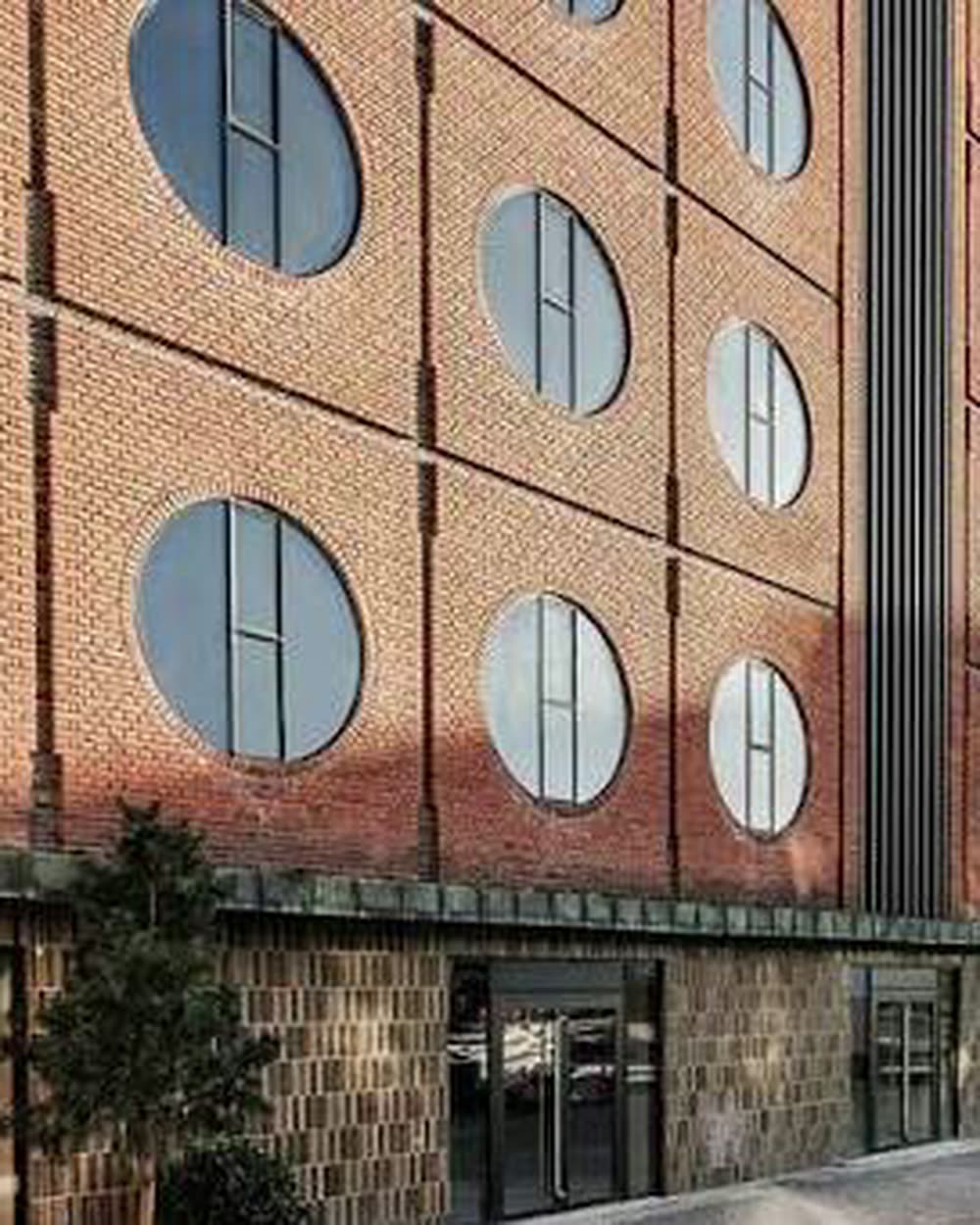 A red-brick facade with circular windows and a hotel entrance at street level &mdash; Hotel Ottilia, Copenhagen, Denmark