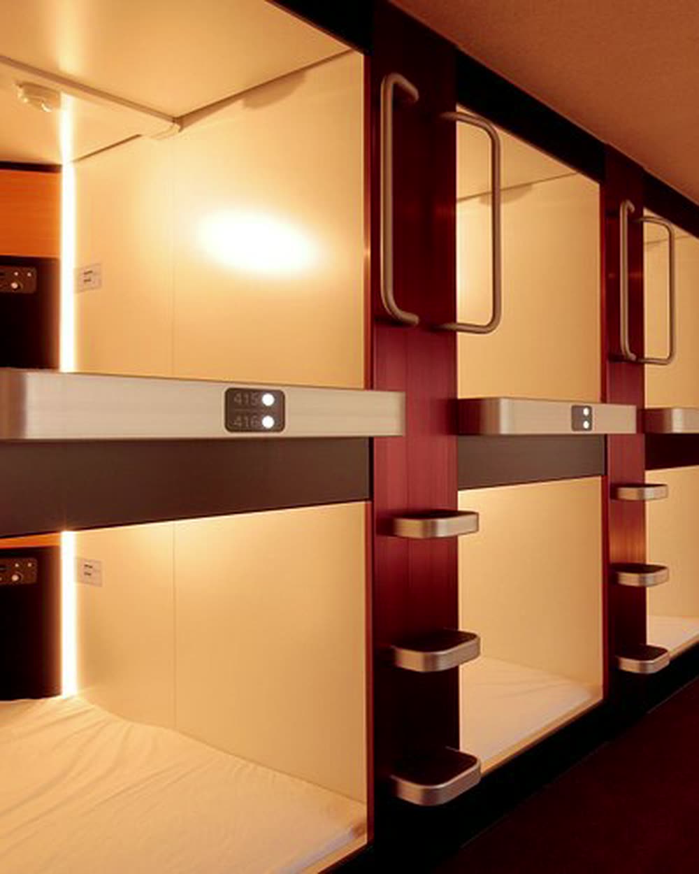 A corridor of stacked capsule openings, interiors lit &mdash; Nadeshiko Hotel Shibuya, Tokyo, Japan