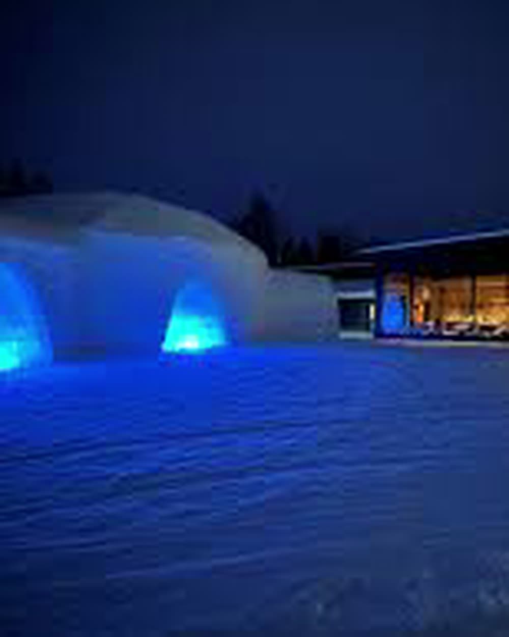 Arched snow entrances lit blue beside a glass-walled hall at night &mdash; Lapland Hotels SnowVillage, Ylläs, Finland