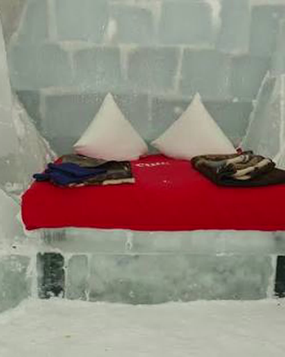 Sawn ice blocks around the bed, light passing through the joints &mdash; Hotel of Ice at Bâlea Lac, Făgăraș Mountains, Romania